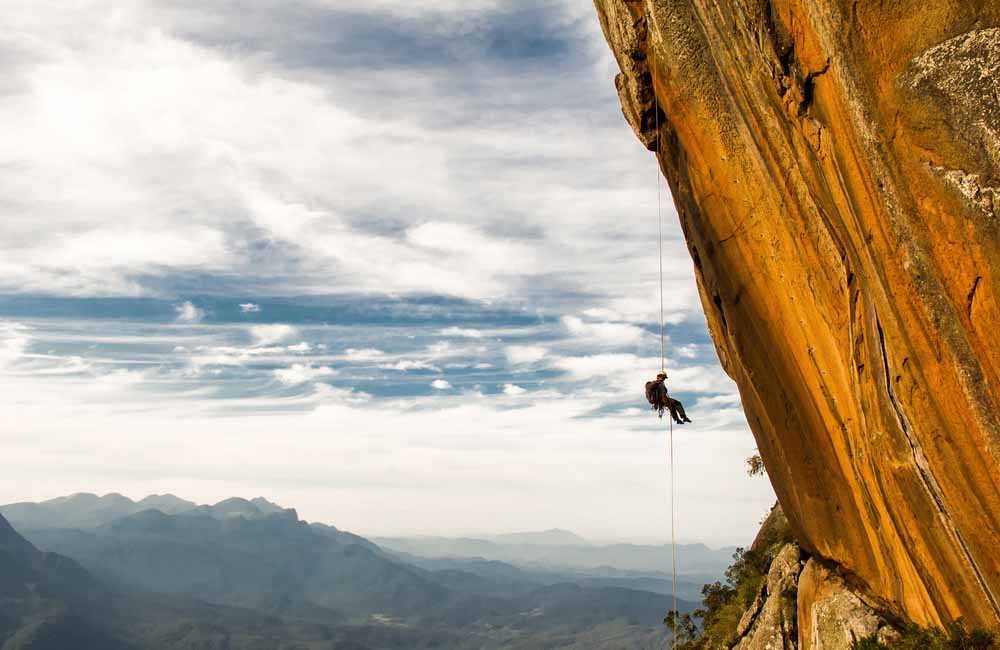 man abseiling on a long climbing rope