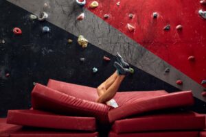 male falling from bouldering wall into crash mats