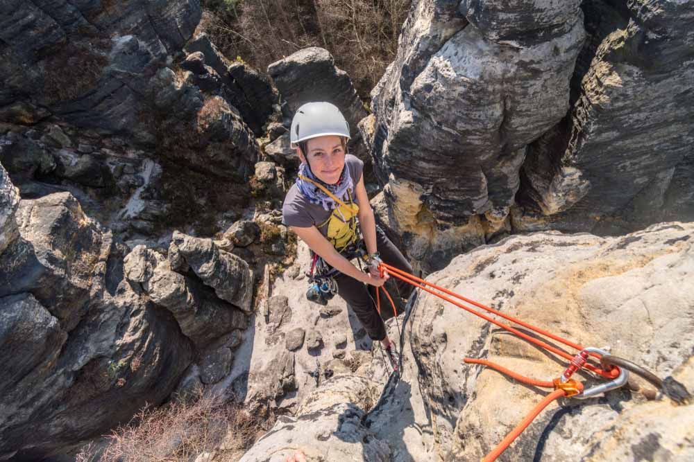 woman rappelling off cliff