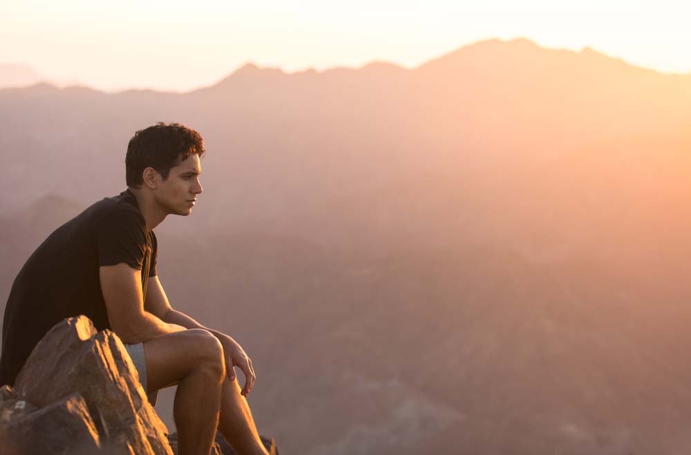 young man looks over the horizon at sunset
