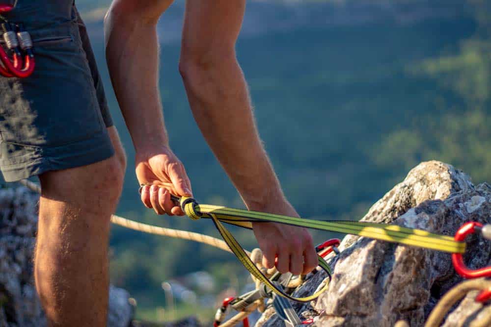 man building a top rope anchor outdoors