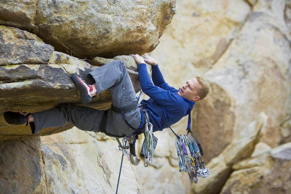 man trad climbing pulling through overhang