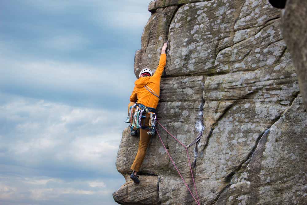 man doing trad climbing on arete