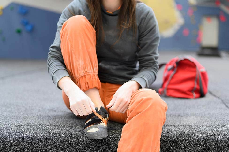 beginner female climber putting on climbing shoes