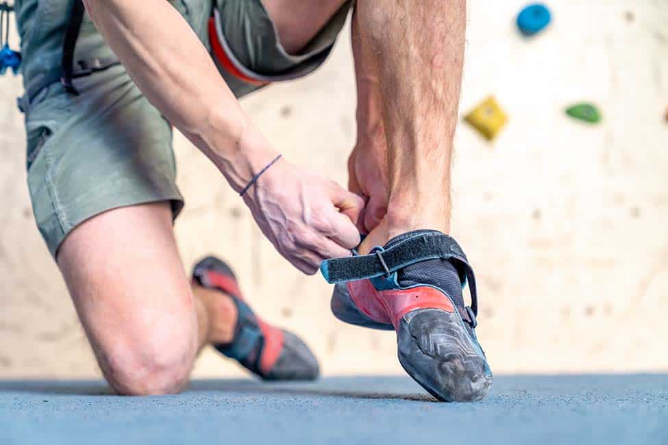 climber putting on tight aggressive shoes