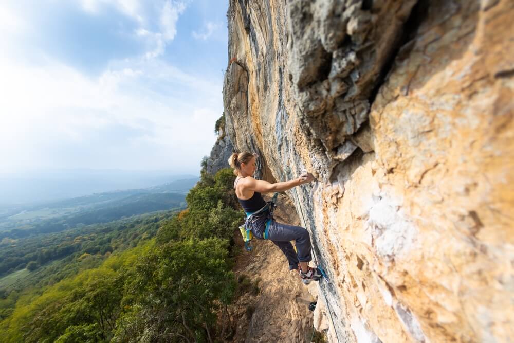 woman free climbing on sunny cliff