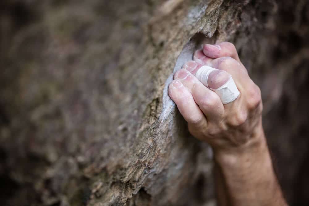 climber with tape on middle finger using full crimp