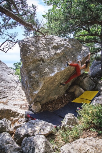 woman bouldering outdoors using multiple crash pads