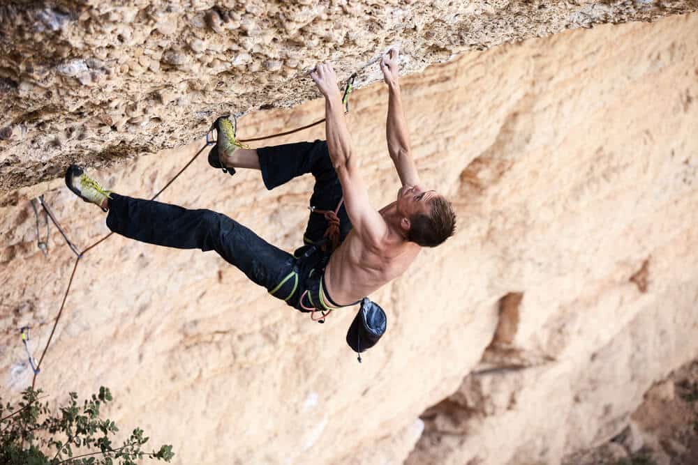 man on difficult overhang sport climbing