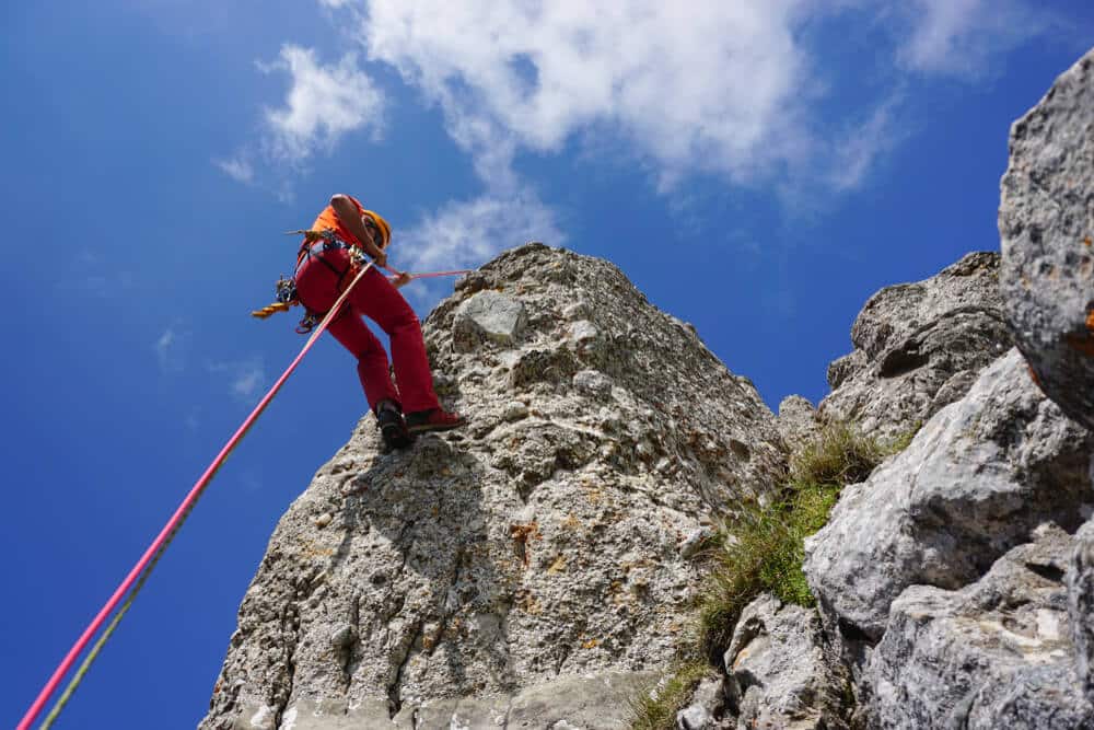 climber rappels off climb with sky in background