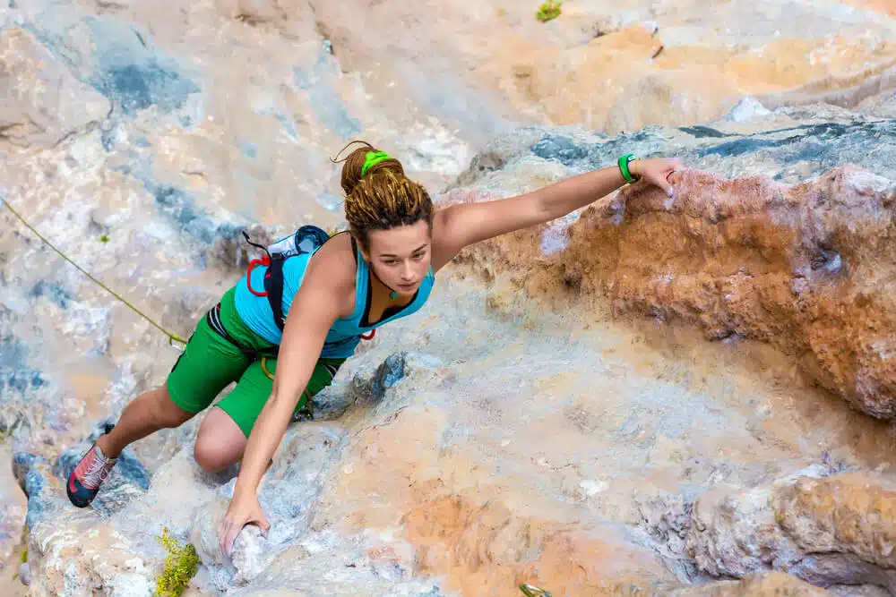 young woman on difficult climb using an outside flag