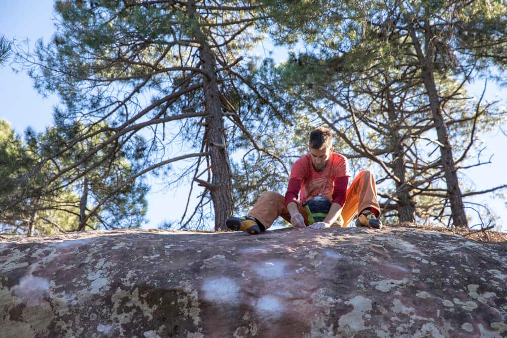 climber sits on top of boulder outdoors