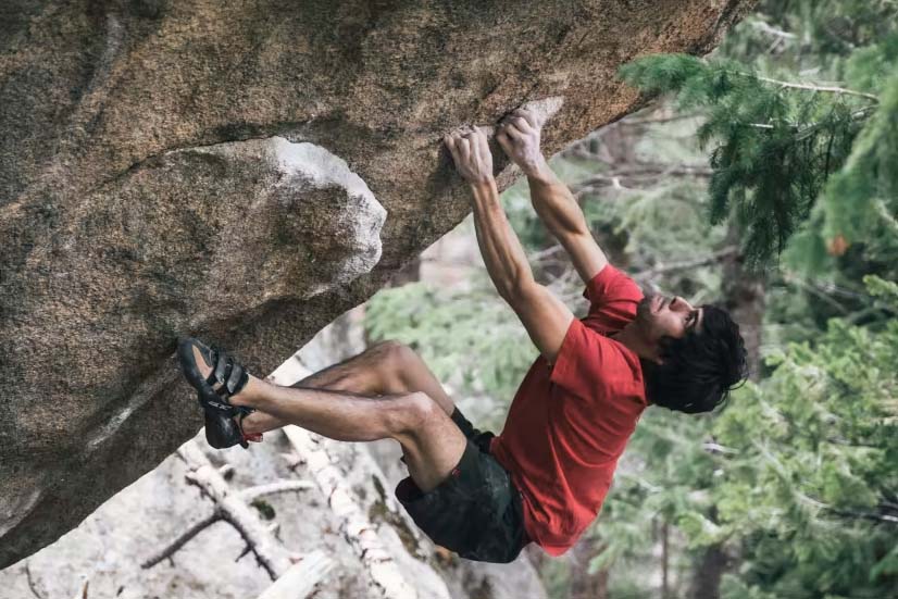climber wearing five ten niad vcs on steep boulder outdoors