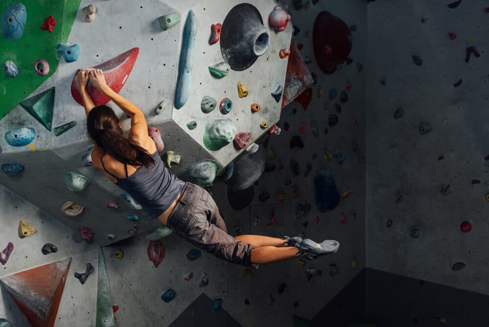 woman catching hold after dynoing on artificial wall
