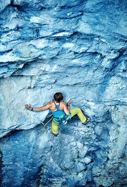 female climber mantles on small ledge
