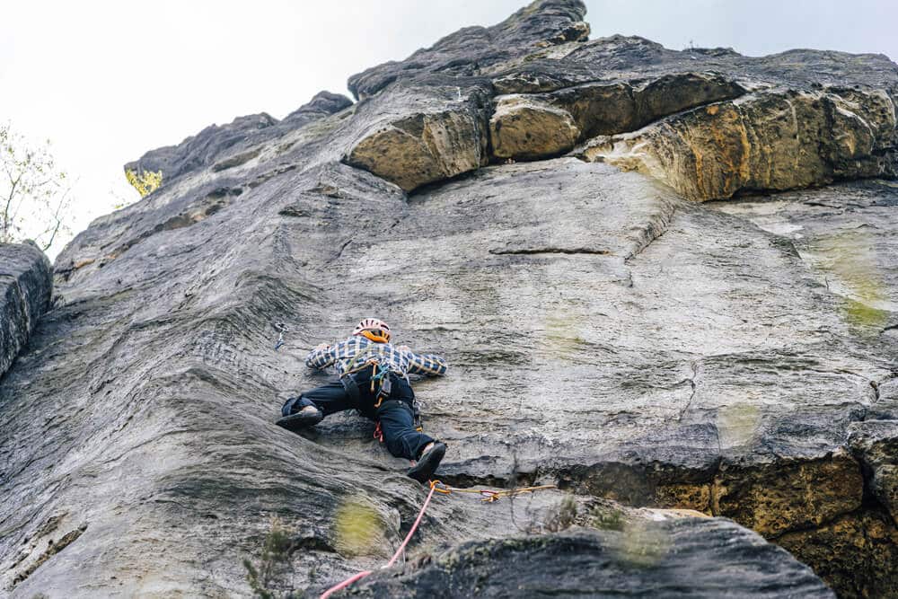 climber wearing helmet doing trad climb outdoors
