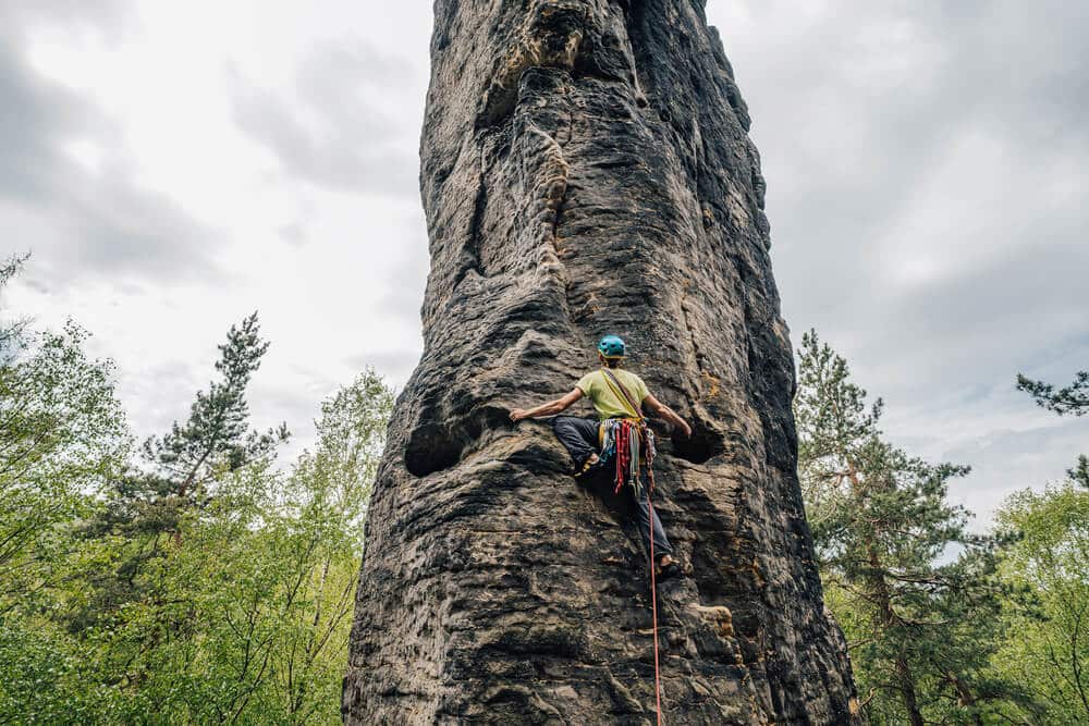 climber wearing helmet doing trad climb outdoors on a stack
