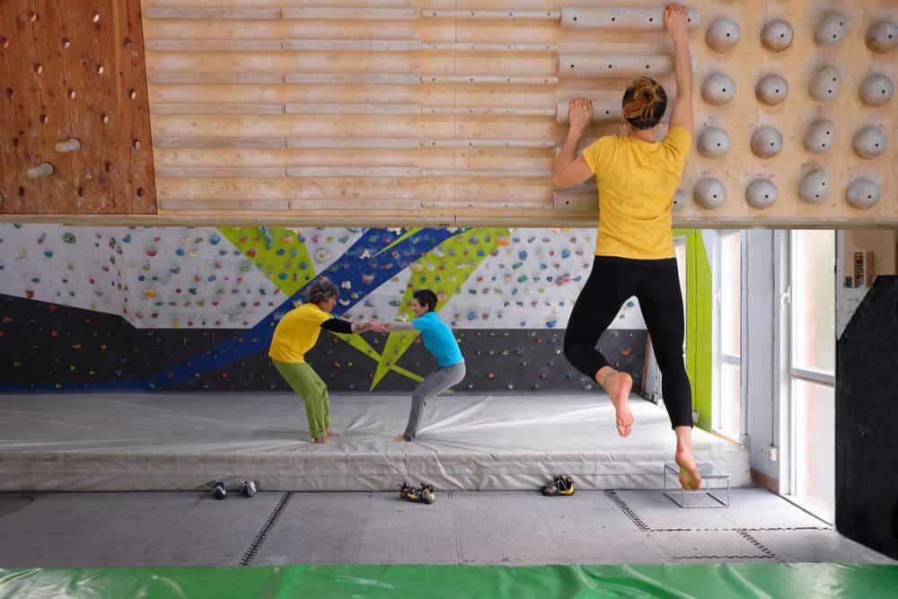 female climber performs campus boarding for strength training